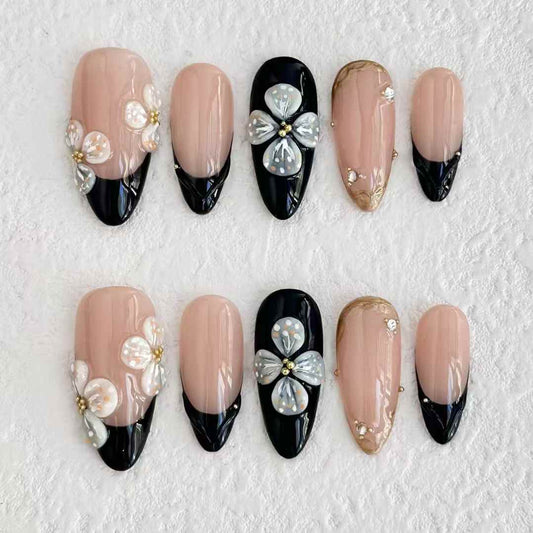 Uñas postizas con diseño floral en 3D en tonos nude y negro